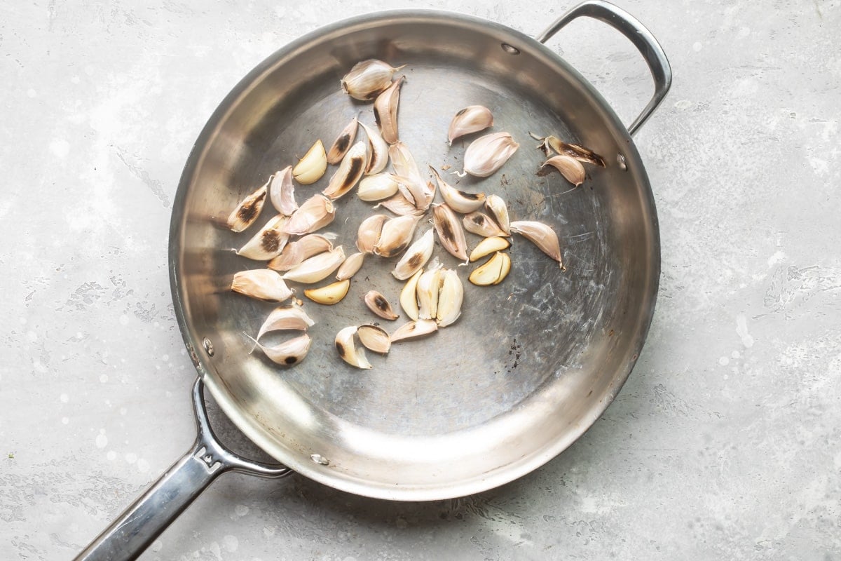 Cloves of garlic toasting in a skillet.
