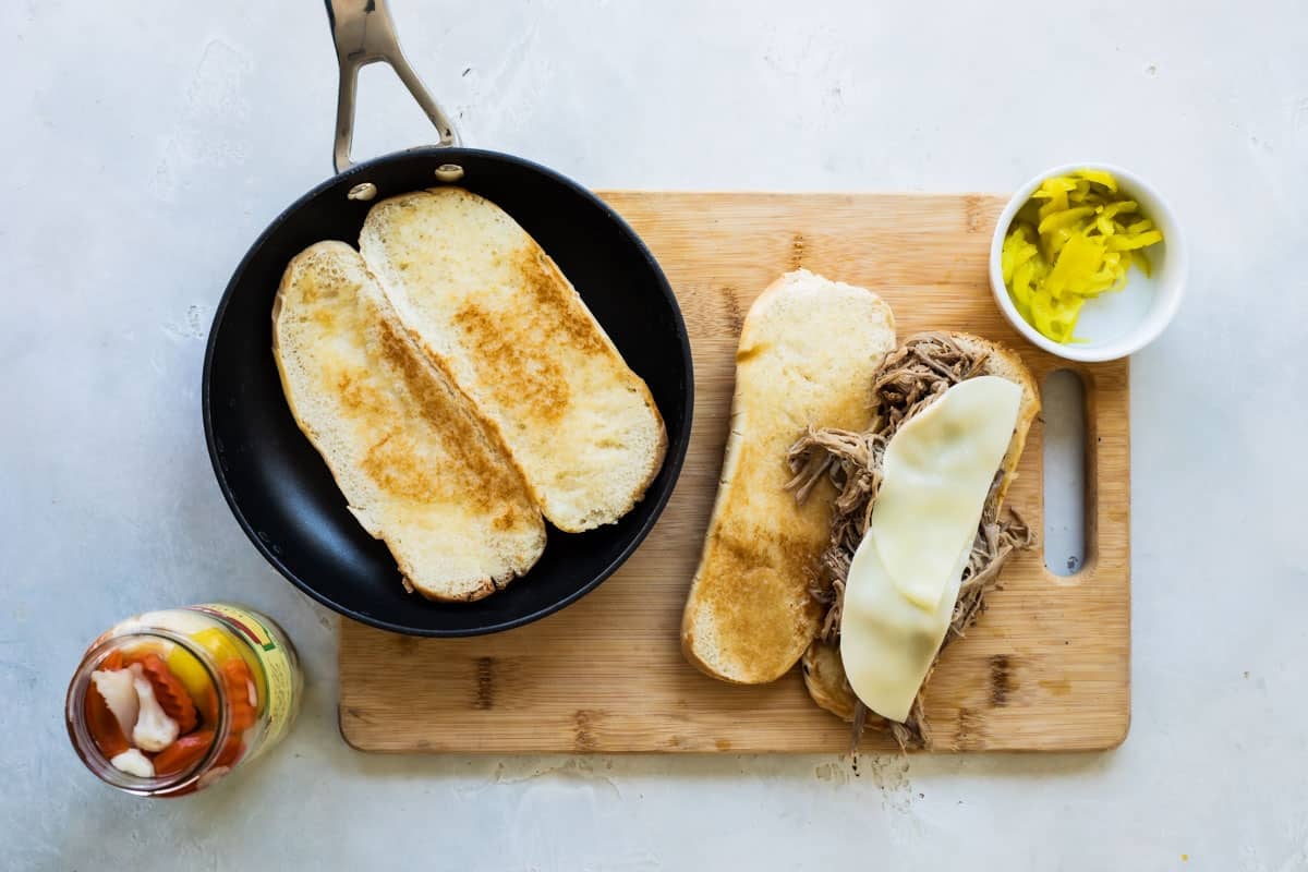 Toasting a bun for an Italian beef sandwich next to an assembled sandwich.