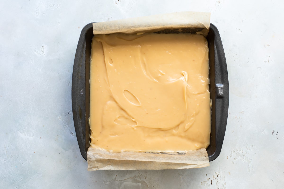 Caramel sauce spread over shortbread in a baking pan.