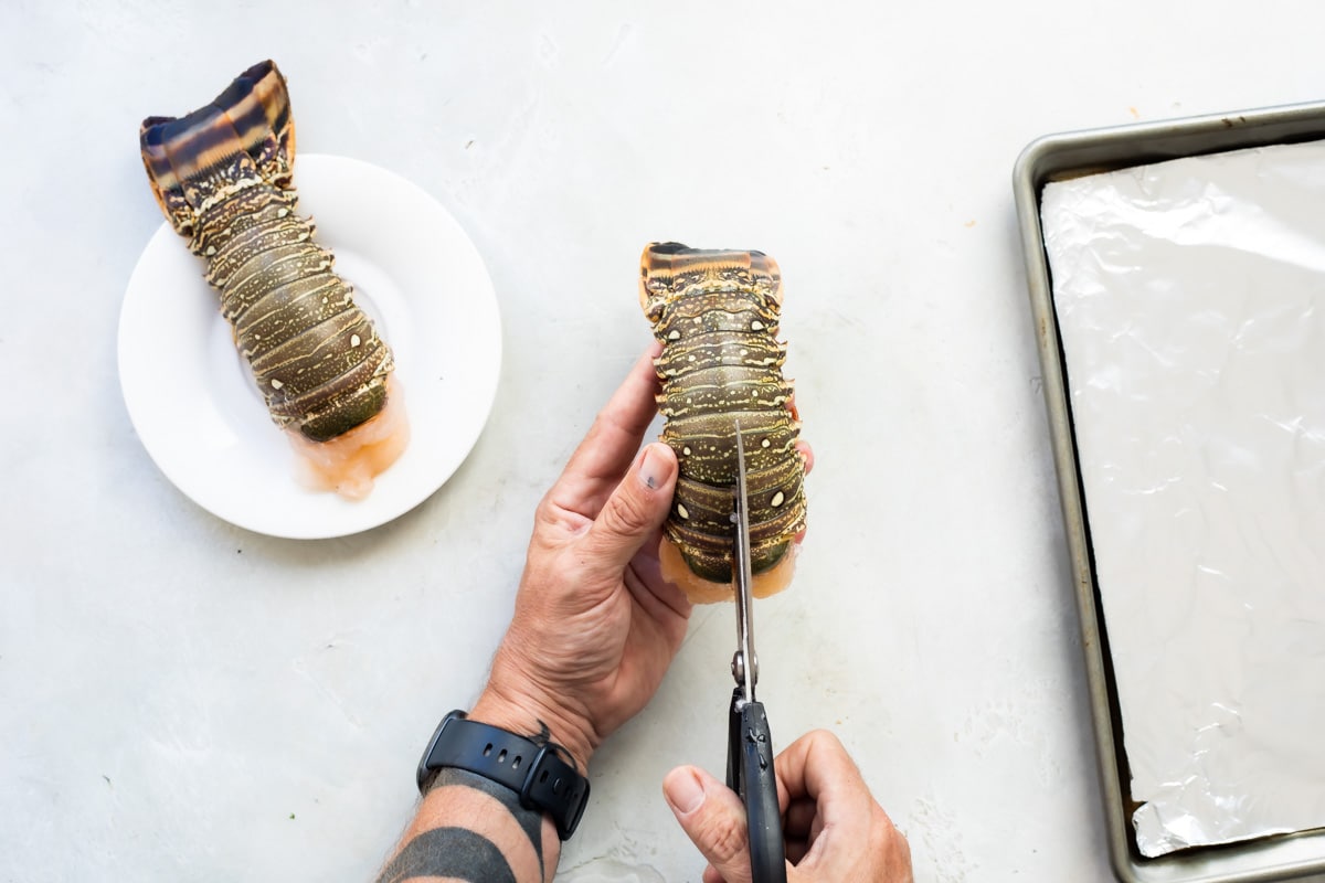 Some slicing the back of a lobster tail to show how to open it.