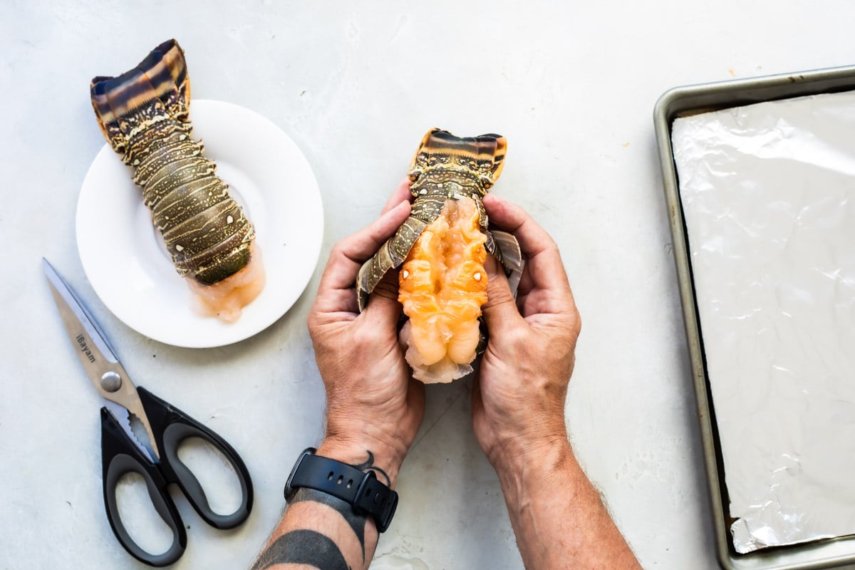 Pulling a lobster tail open so it puffs up when cooking.