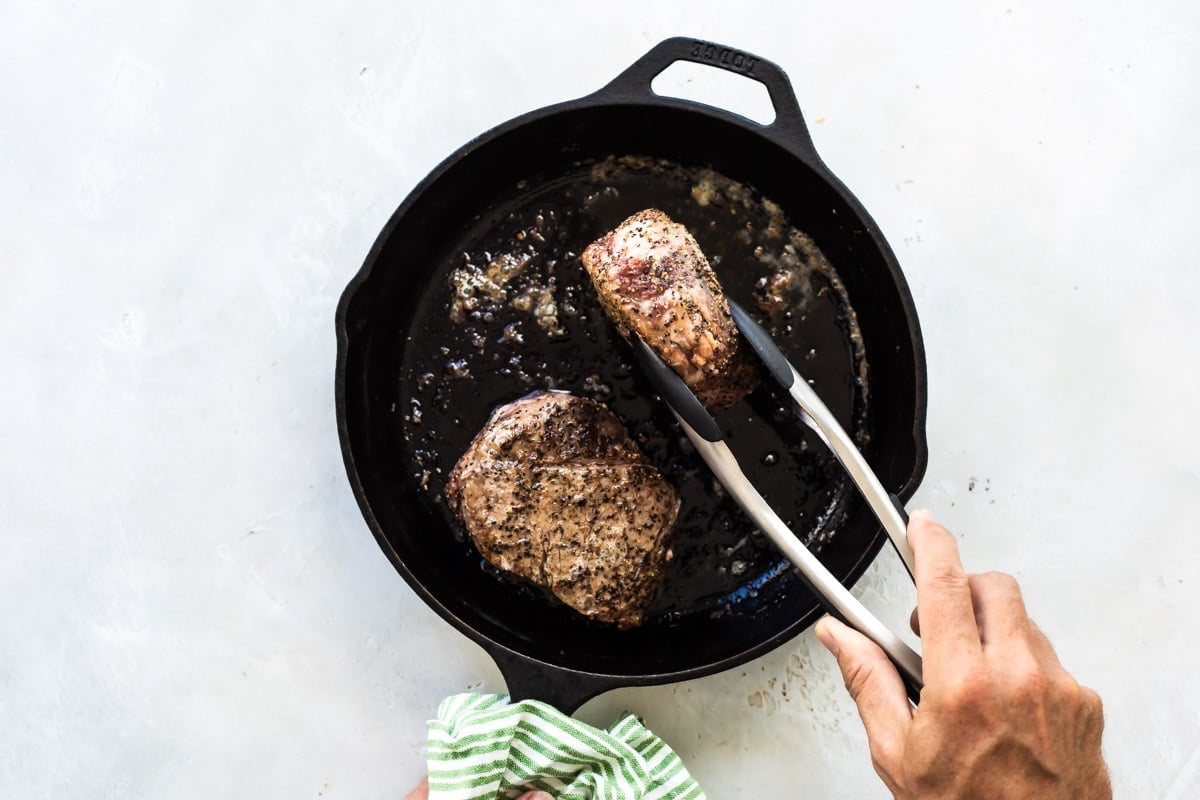 Searing filet mignons in a skillet.