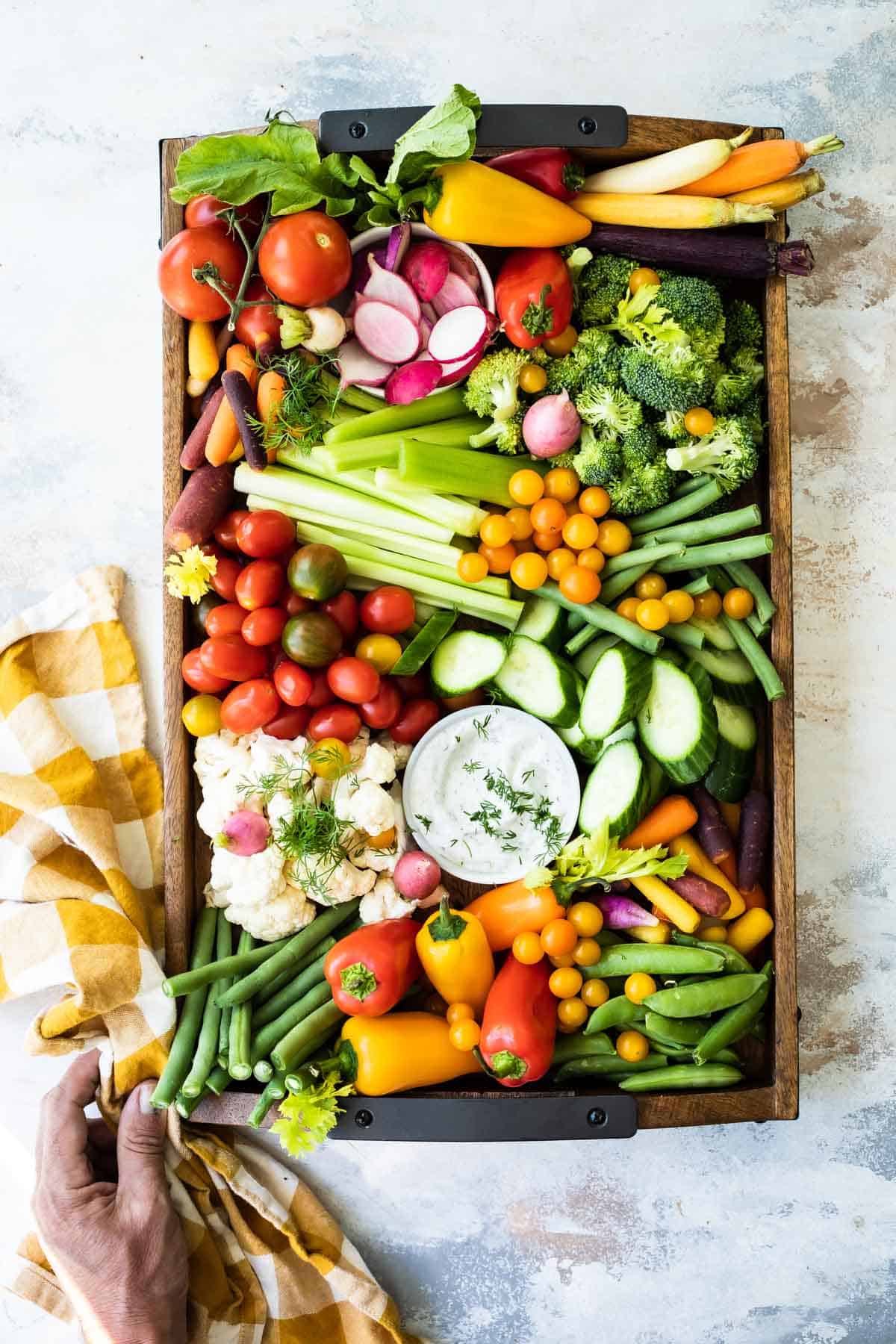 A platter full of fresh vegetables with a bowl of veggie dip.