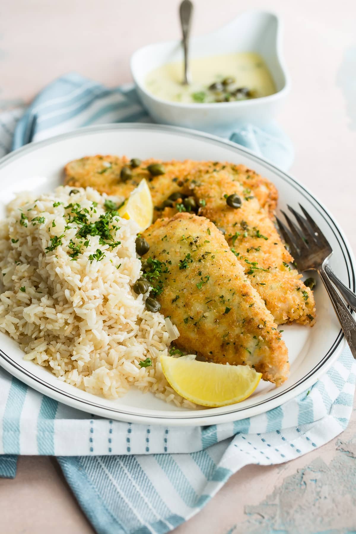 An angled shot of lemon rice and pilaf on a white plate.