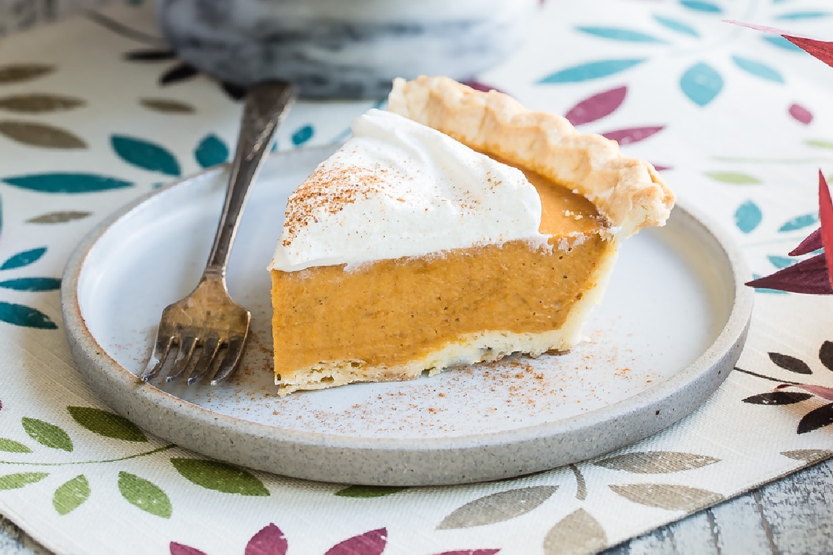 A slice of pumpkin pie with whipped cream on top.