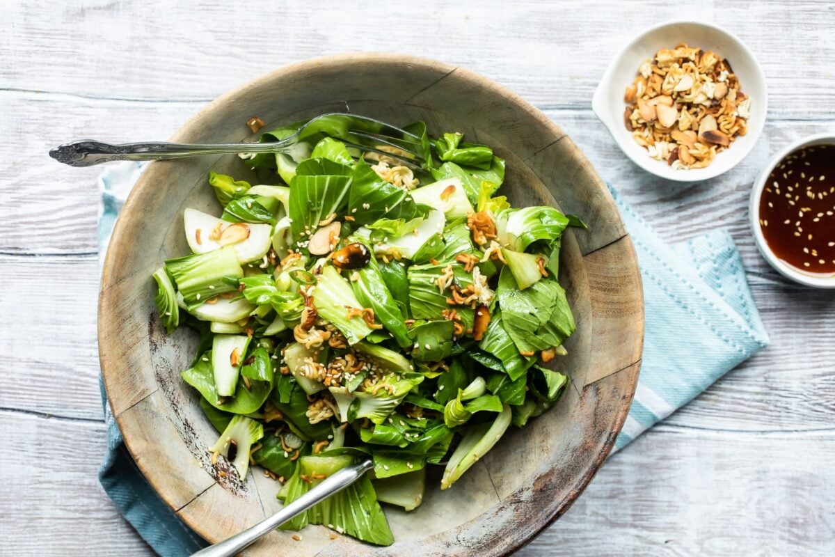 Baby bok choy salad with sesame dressing in a wooden bowl.