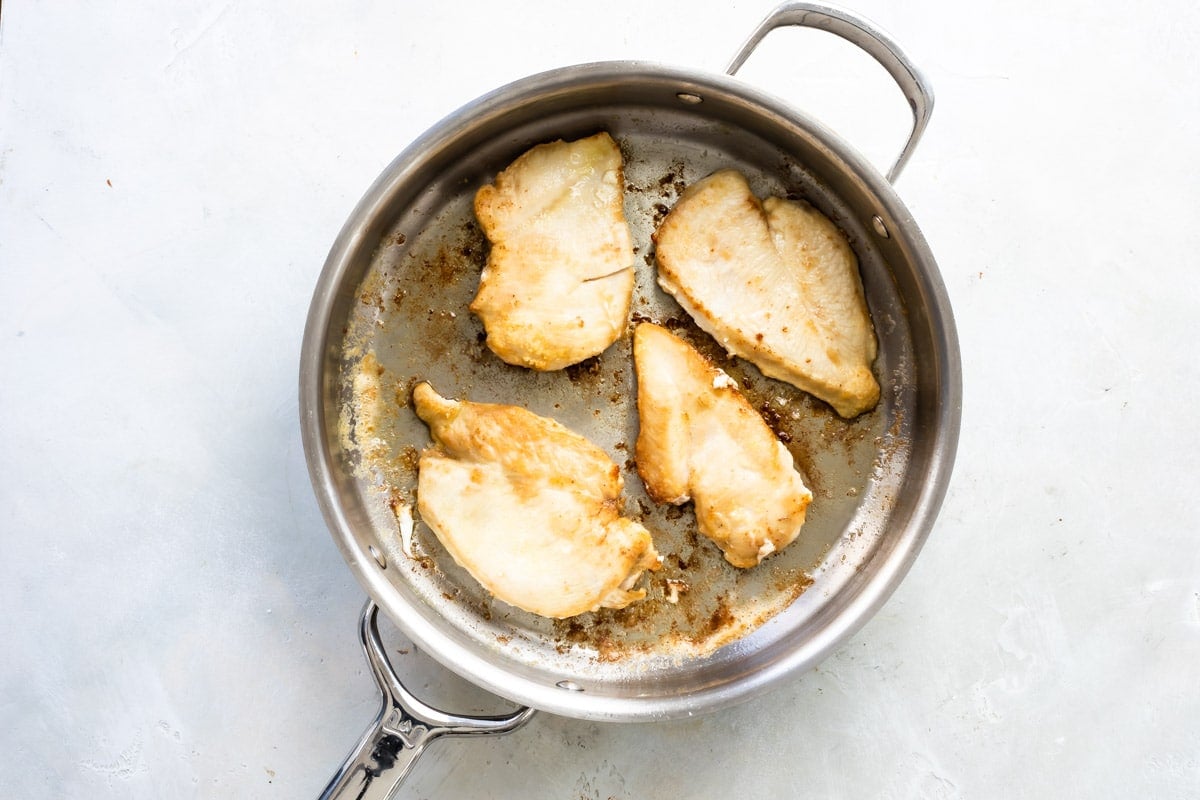 Sautéing chicken cutlets in a skillet.