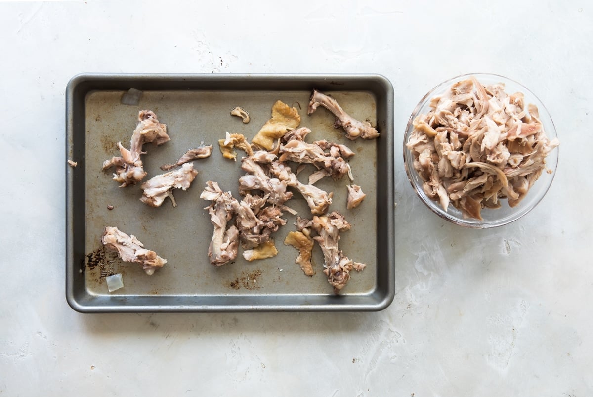 Chicken being shredded from bones and skin.