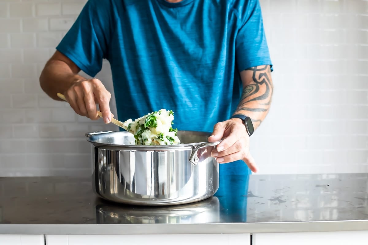 Colcannon being scooped out of a silver stock pot.