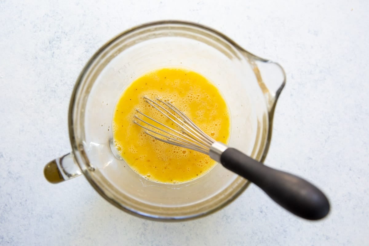 Eggs, salt, and pepper whisked together in a glass bowl.