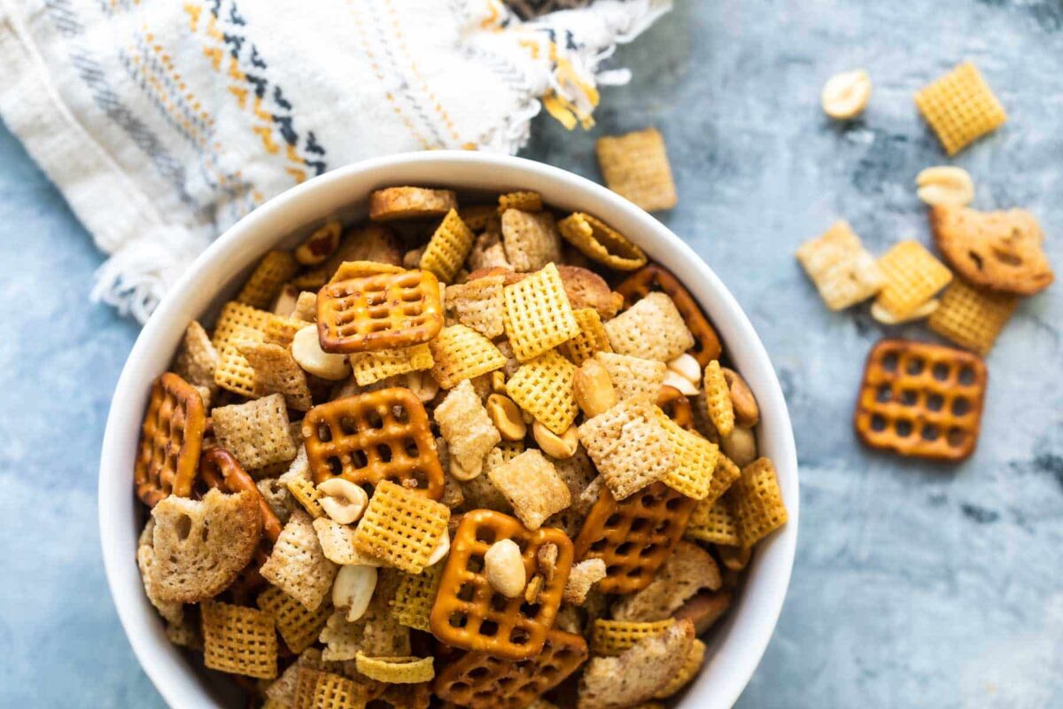 A bowl of Chex mix on a gray background.