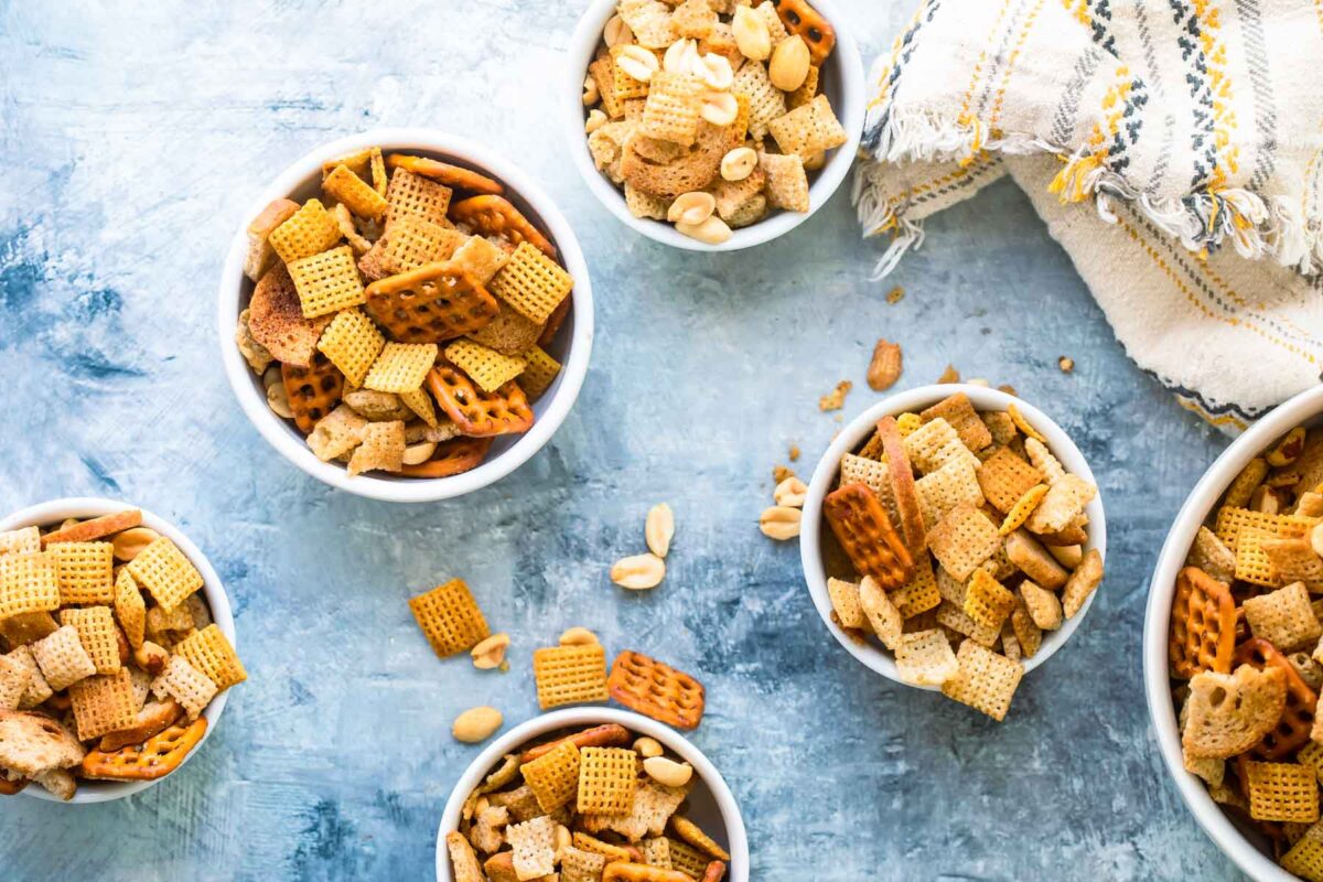 Bowls of chex mix on a gray background.