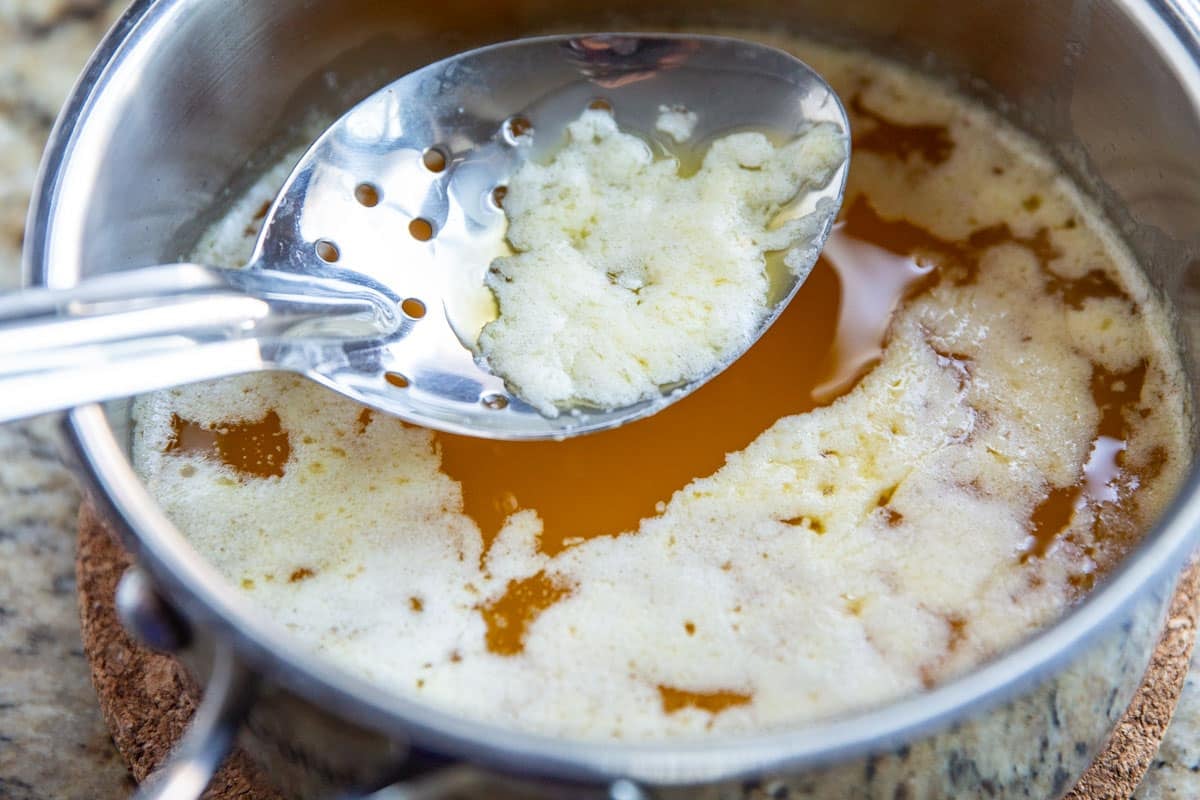 Skimming solids off the top of clarified butter.