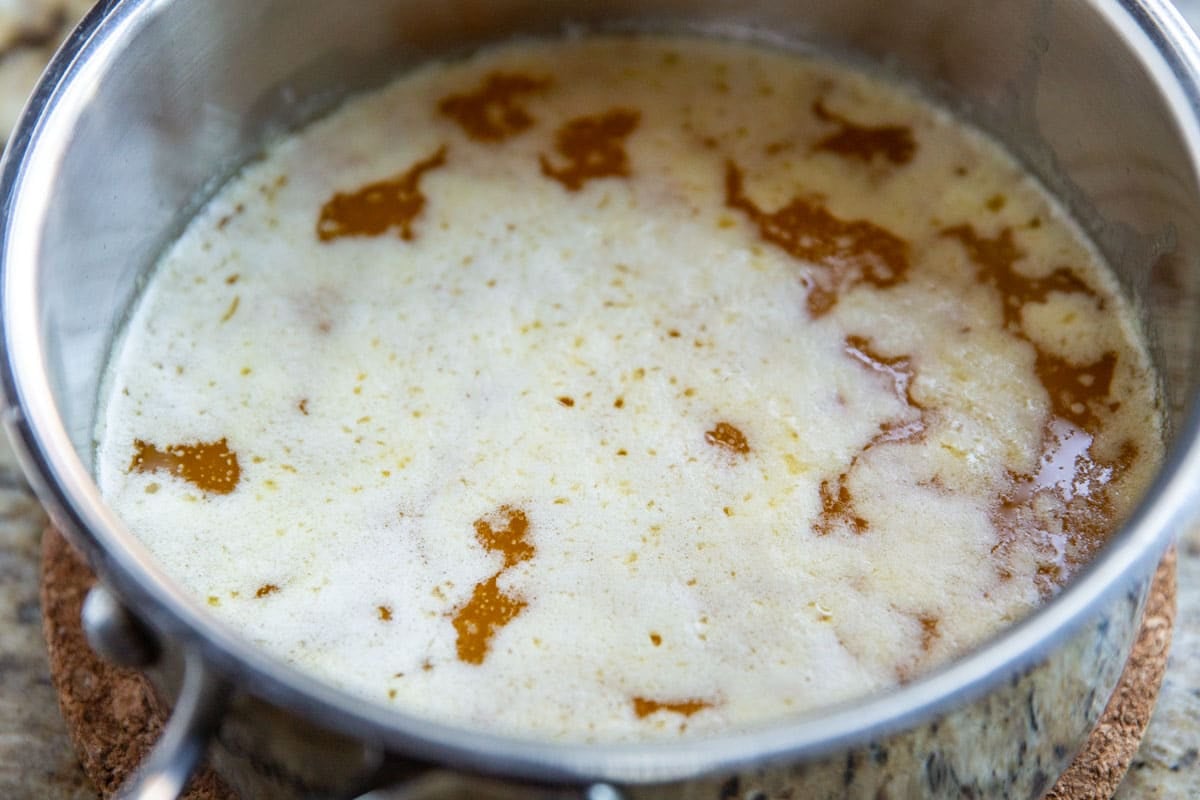 Skimming solids off the top of clarified butter.