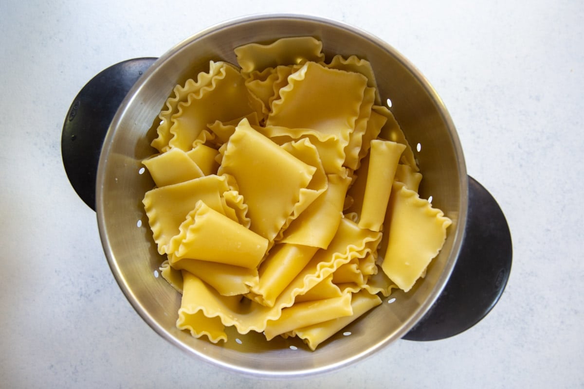 A colander with lasagna noodles draining in it.