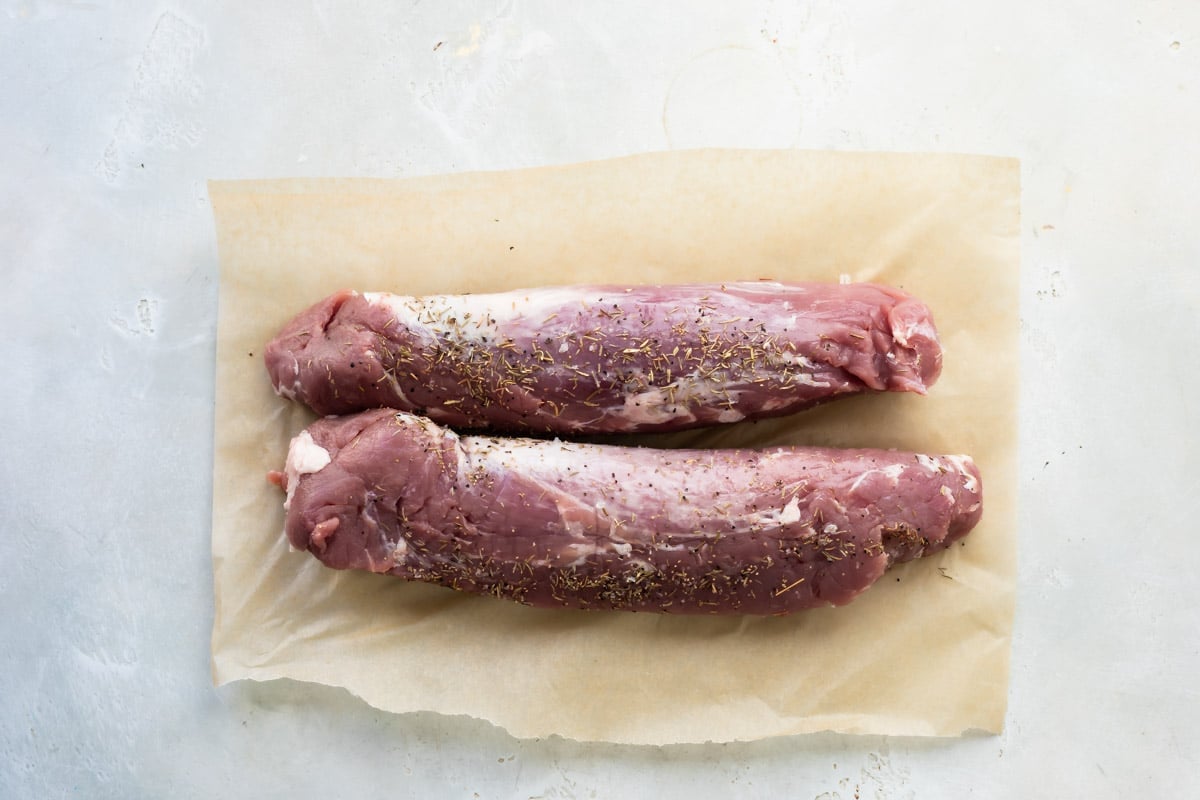 Pork tenderloins on a piece of parchment paper coated in spices.