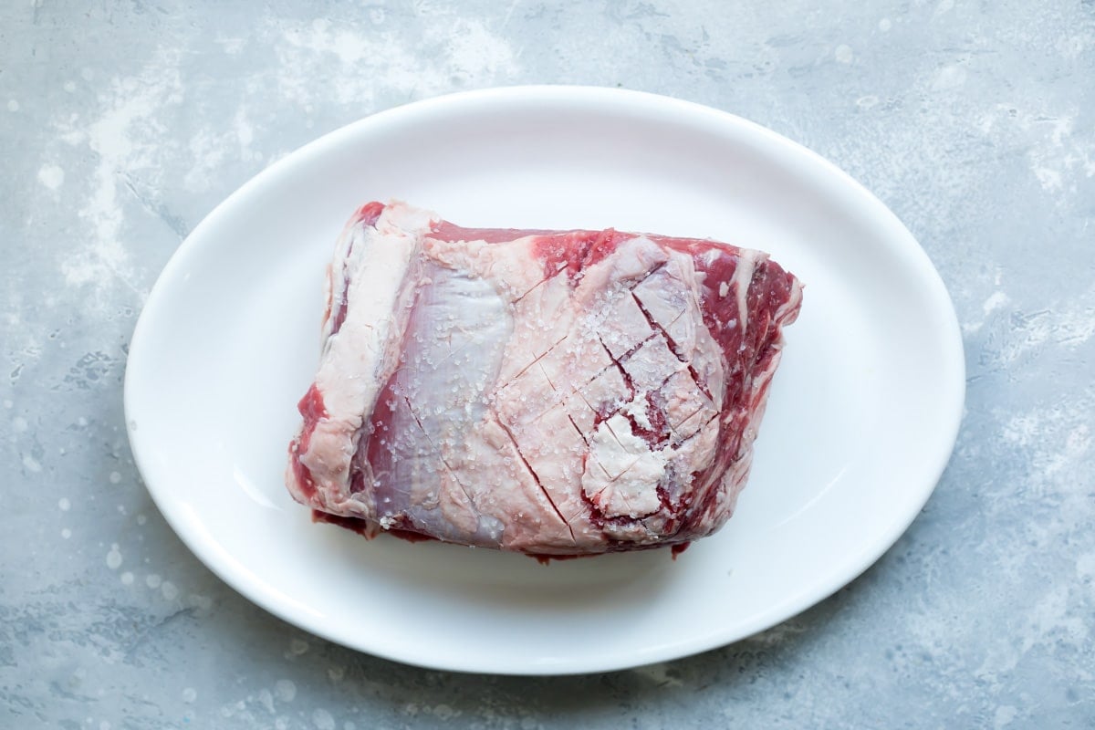 Raw prime rib on a white platter.