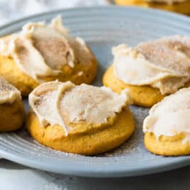 Frosted pumpkin cookies on a gray plate.