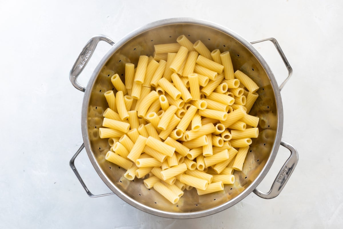 A colander filled with cooked rigatoni.