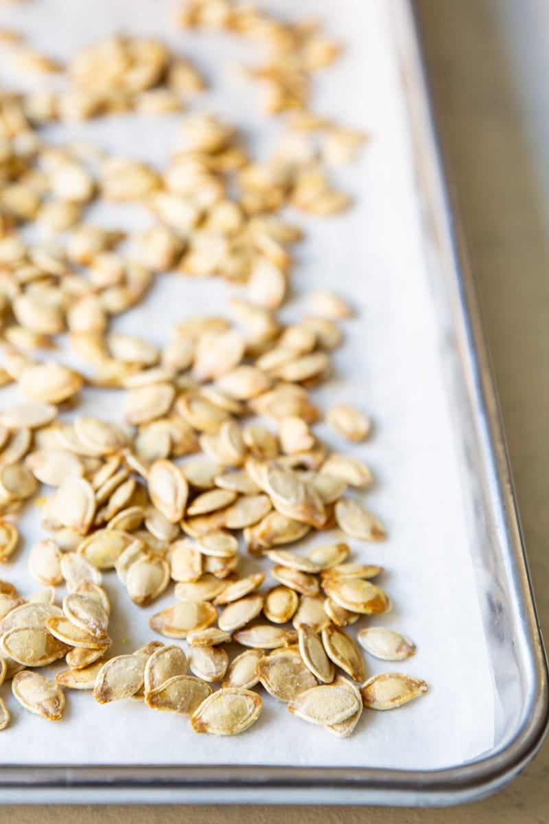 Roasted pumpkin seeds on a baking sheet.