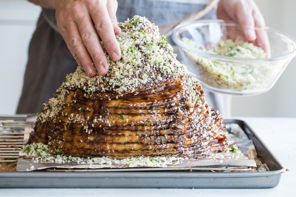 Pressing crumbs on to a smoked ham.