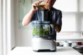 Someone making chimichurri sauce in a food processor.
