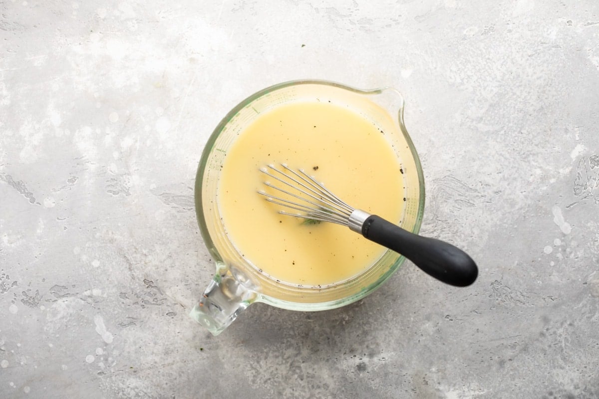 Eggs, broth, and spices whisked together in a bowl.