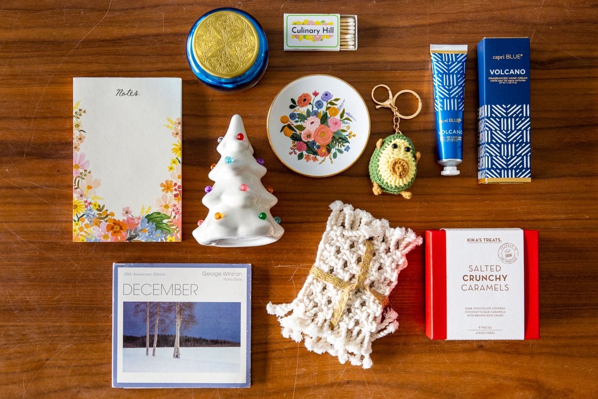 A holiday box filled with presents with wrapping paper nearby.