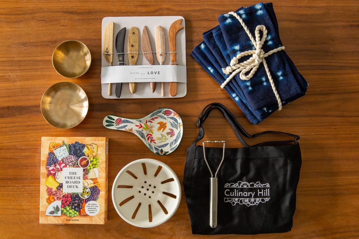 A holiday box filled with presents with wrapping paper nearby.