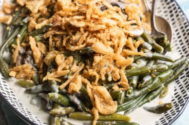 Slow cooker green bean casserole on a patterned platter.