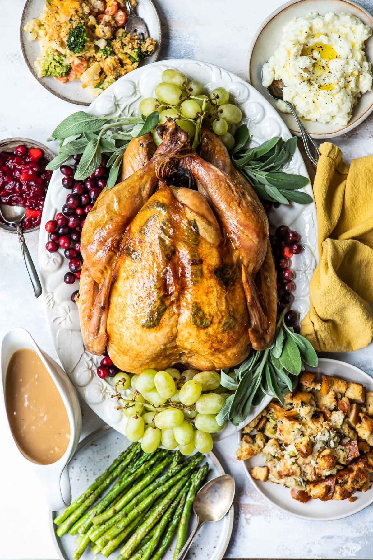 A roasted turkey on a platter with fruit.
