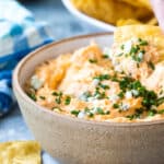 Someone dipping a tortilla chip in buffalo chicken dip.