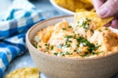 Someone dipping a tortilla chip in buffalo chicken dip.