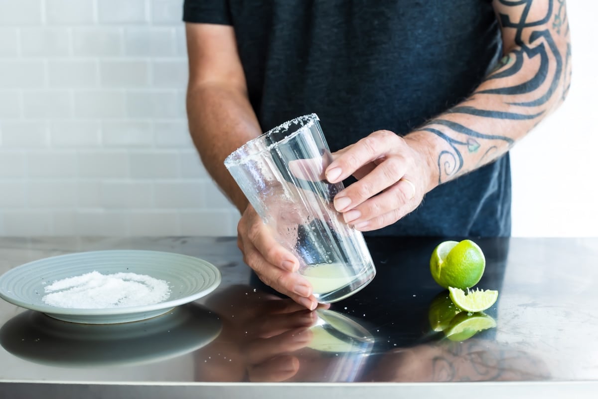 Someone holding a pint glass with lime juice in it.