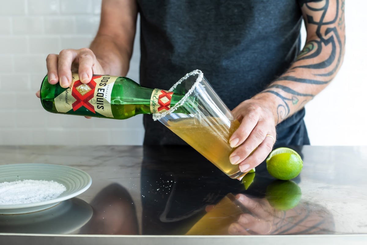 Someone pouring a beer into a salt rimmed pint glass.