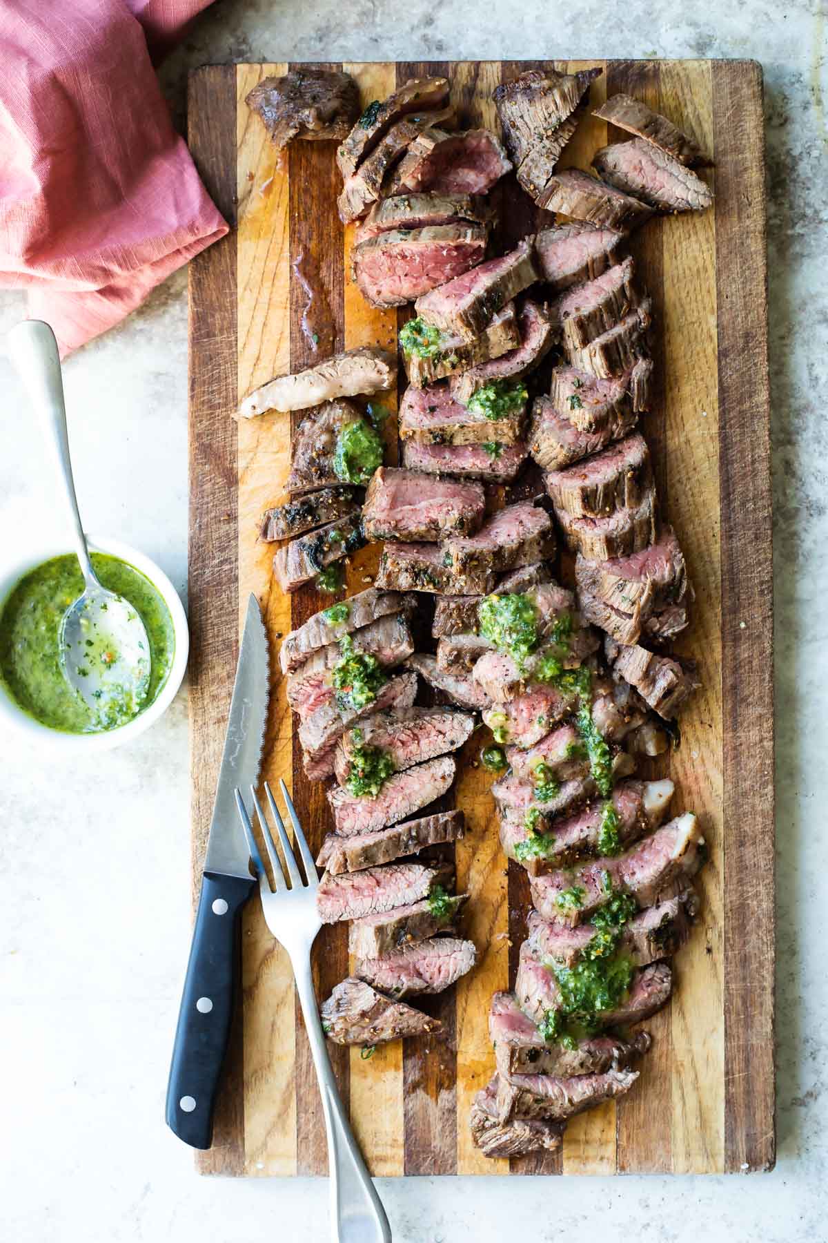 Chimichurri steak on a wooden cutting board.