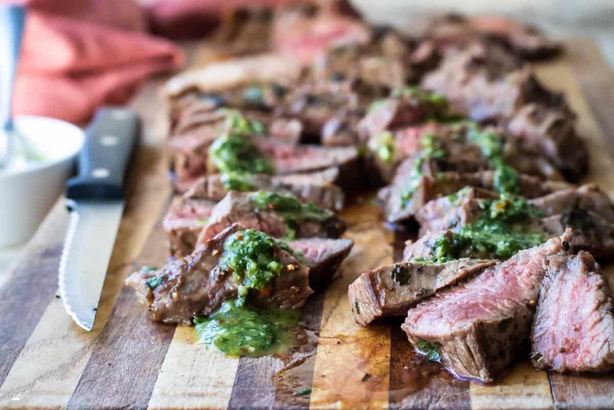 Chimichurri steak on a wooden cutting board.