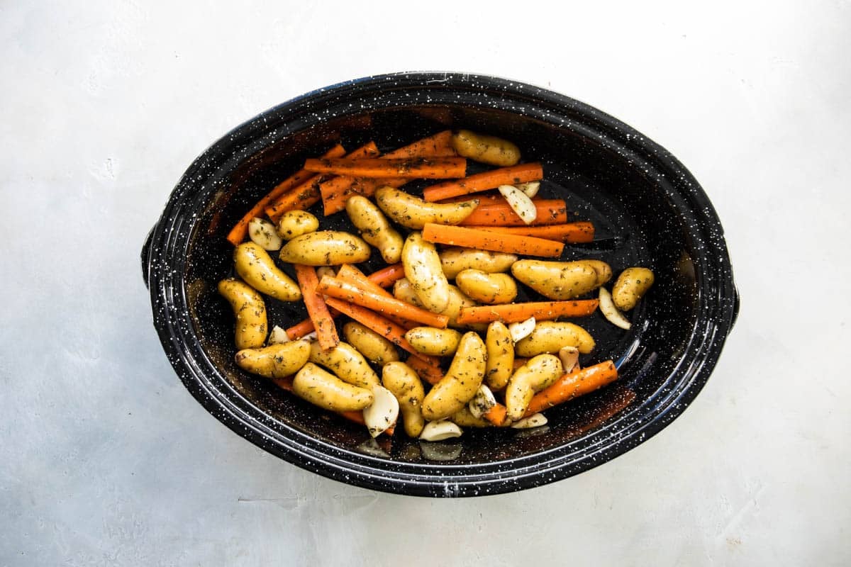 Potatoes and carrots in a roasting pan before being baked.