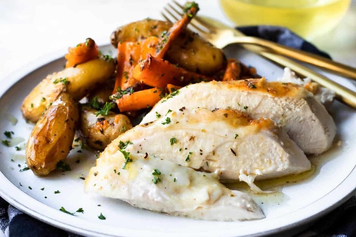 Garlic butter roasted chicken and vegetables on a white plate.