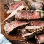 Grilled New York strip slices on a wooden cutting board.