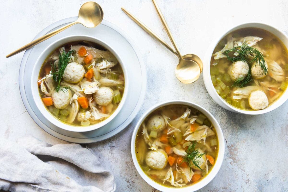White bowls filled with matzo ball soup.
