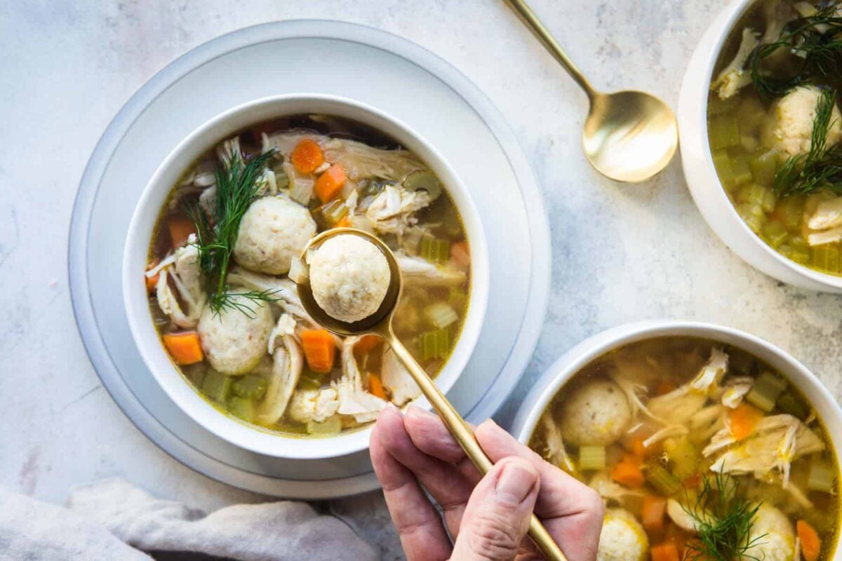 White bowls filled with matzo ball soup.