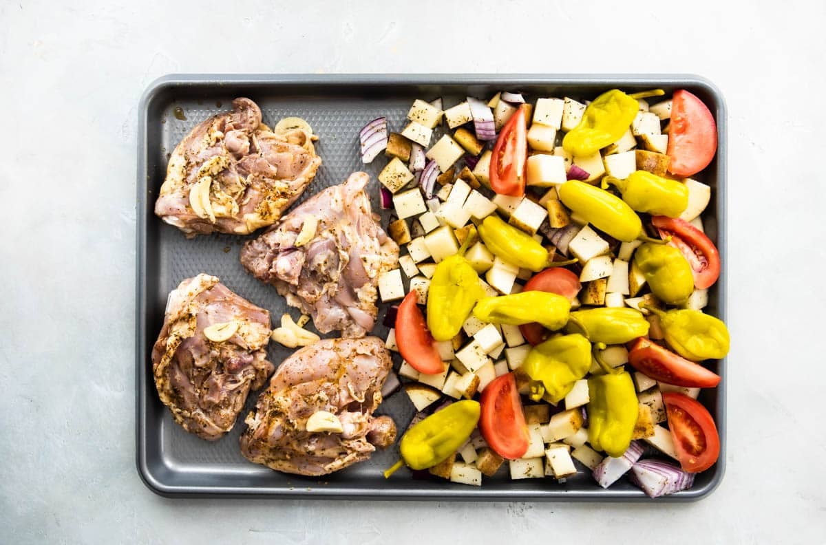 Sheet pan Greek chicken on a baking sheet before being baked.