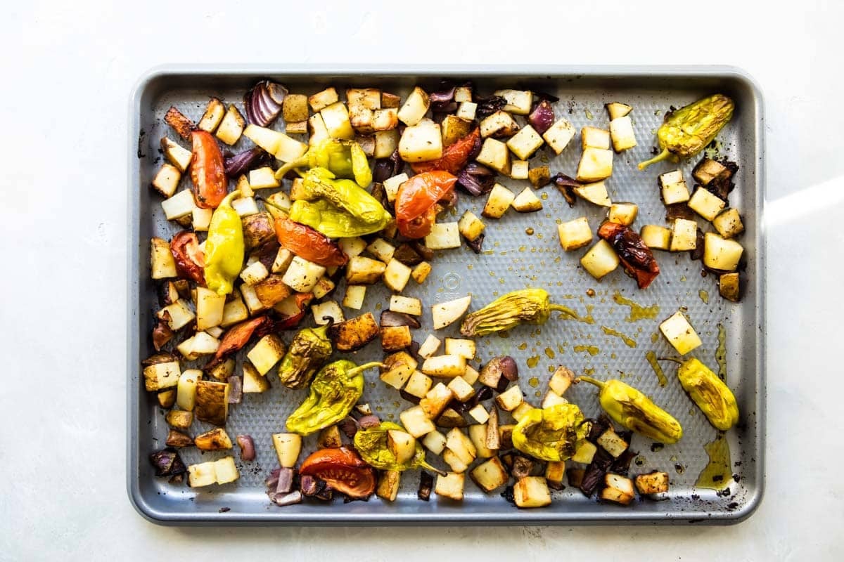 Greek chicken vegetables on a baking sheet after being roasted.