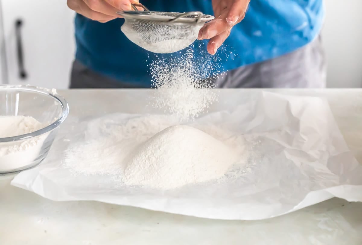 Sifting flour on to parchment paper.
