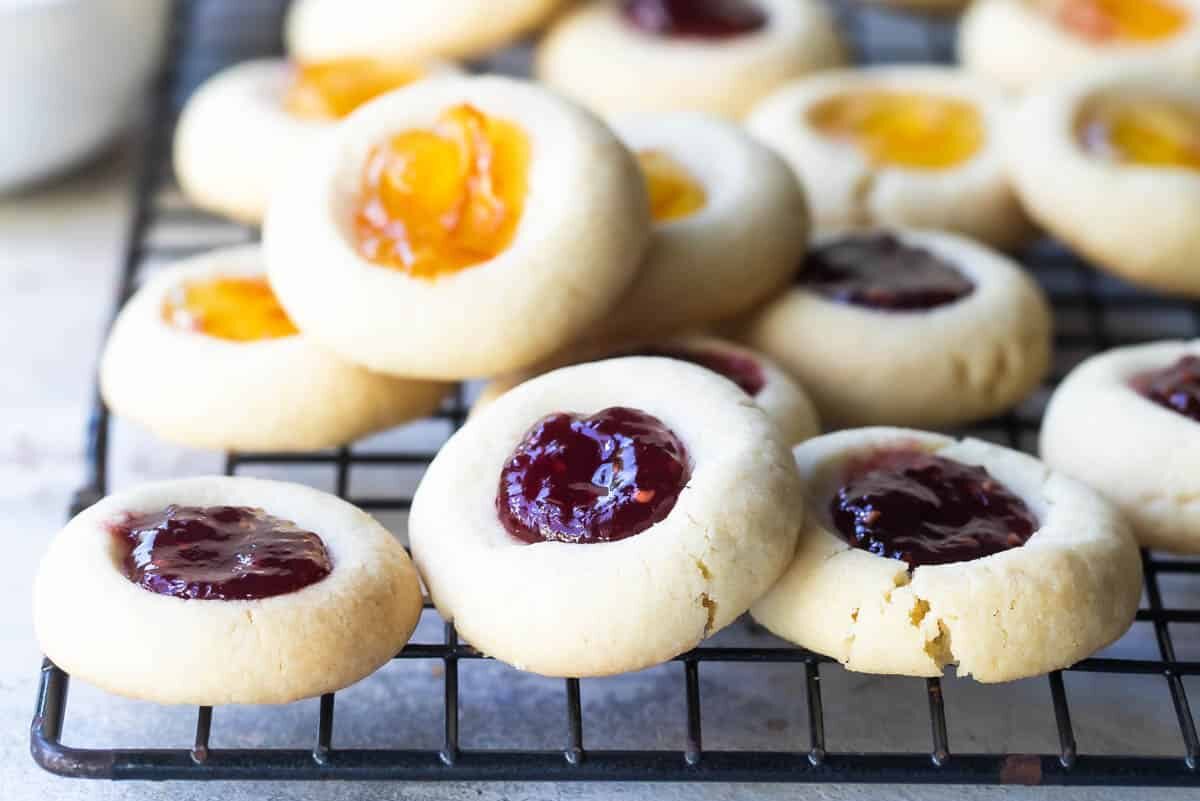 A pile of thumbrpint cookies on a baking rack.