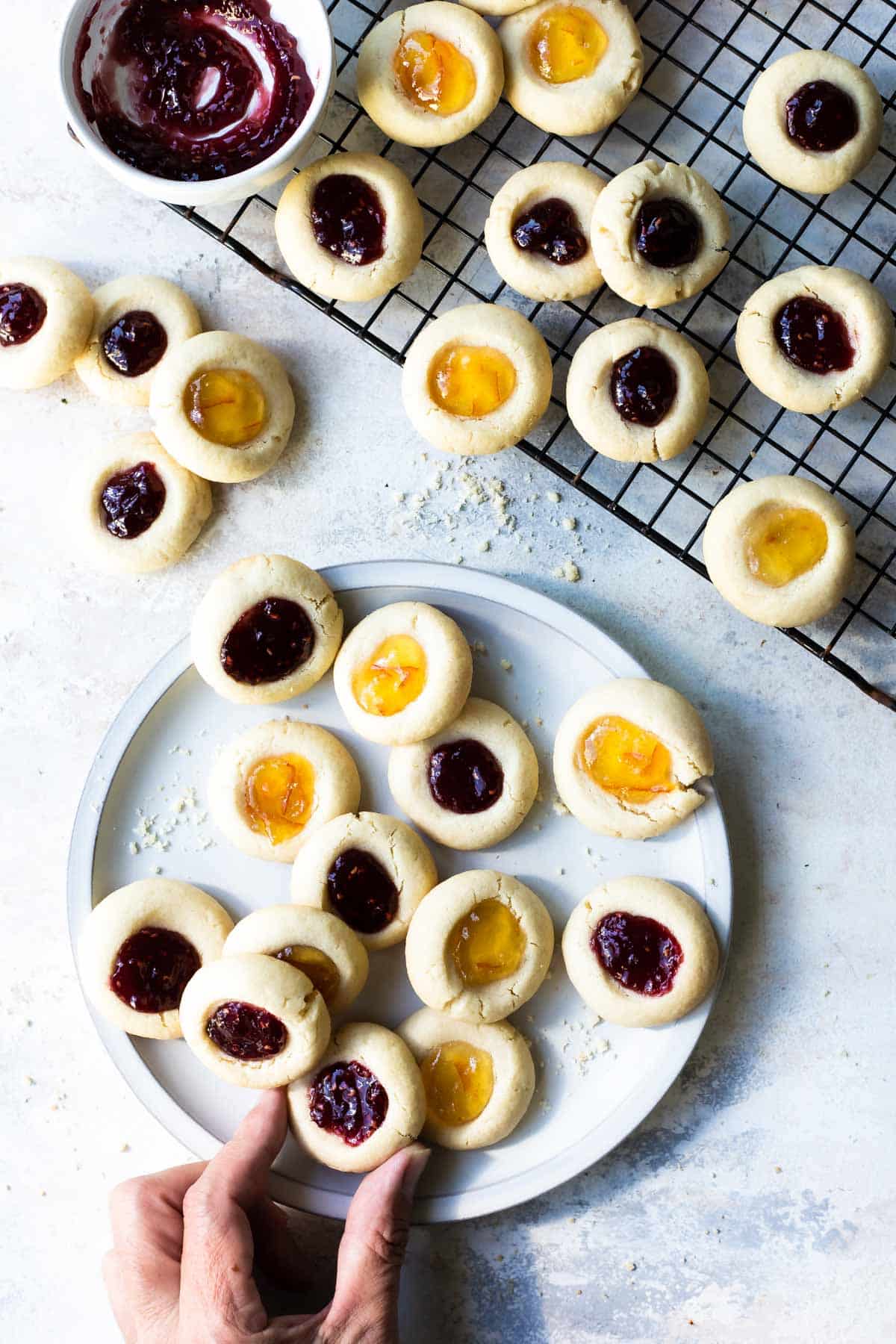 A pile of thumbrpint cookies on a baking rack.