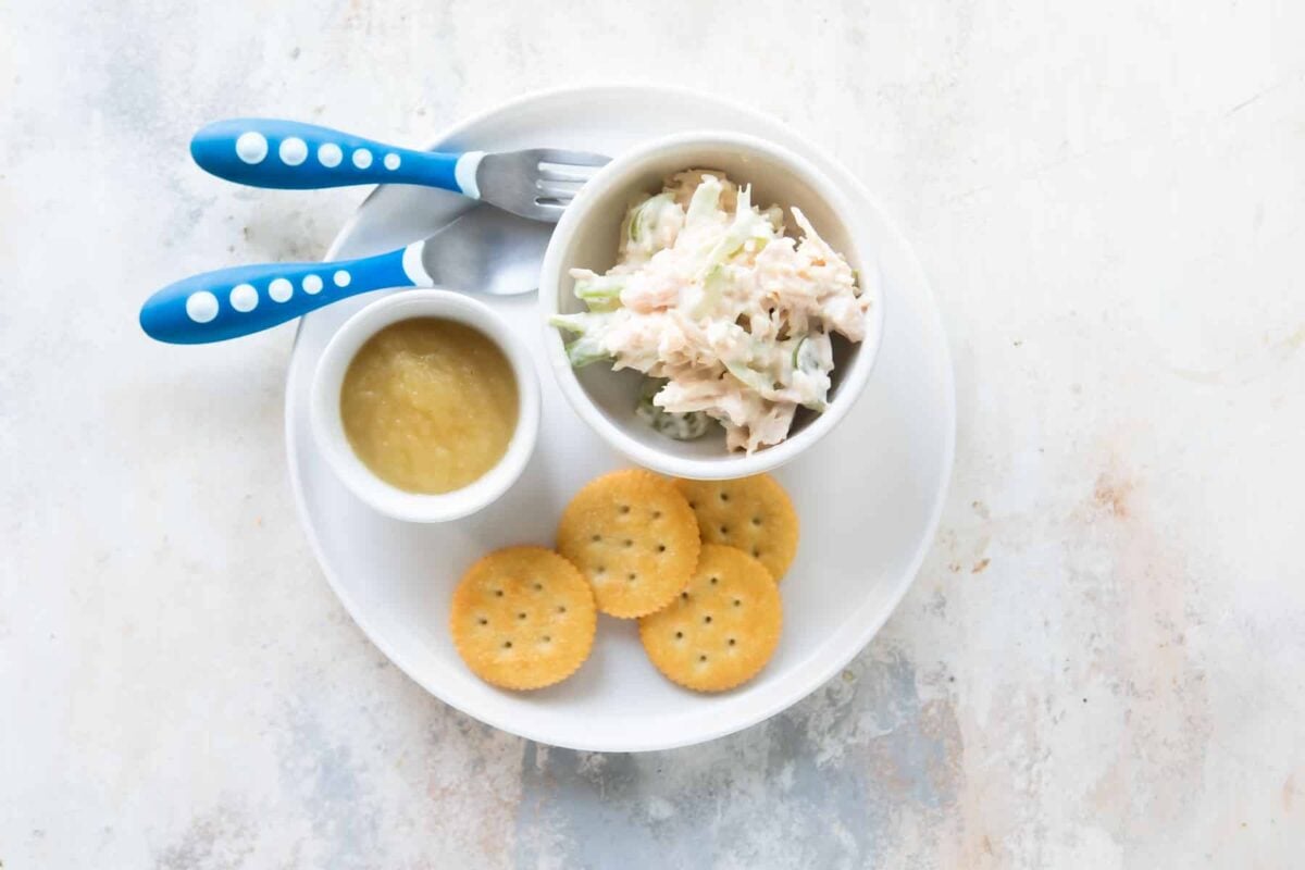 A toddler lunch of chicken salad, crackers and applesauce.