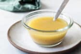 Apple cider vinaigrette in a clear bowl with a spoon.