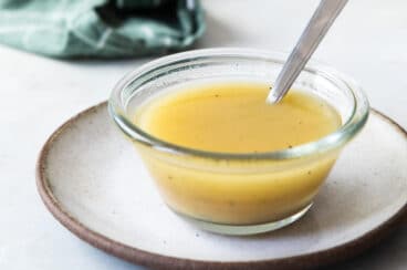 Apple cider vinaigrette in a clear bowl with a spoon.